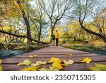Family crosses the river on wooden bridge in autumn.