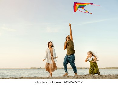 Family with cute klittle girl running through beach letting kite fly. Young father and mother with daughter child kid playing outside with flying kite together - Powered by Shutterstock