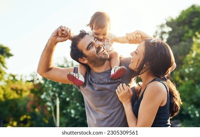 Family, dad and daughter on shoulders in park with mom, happiness or love in summer sunshine. Young couple, baby girl or laugh together for freedom, bond or holding hands for care, backyard or garden