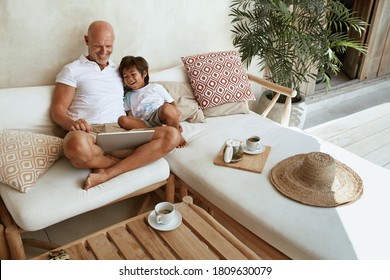 Family. Dad And Son With Tablet Resting In Tropical Villa Patio And Enjoying Weekend. Happy Father And Little Boy Having Fun With Digital Technology On Summer Vacation.