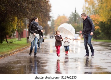 Family with daughters under the umbrellas, running. Rainy day. - Powered by Shutterstock