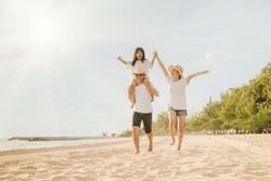 Family Day. Happy Family People Having Fun In Summer Vacation Run On Beach, Daughter Riding On Father Back And Mother Running At Sand Beach, Family Trip Playing Together Outdoor, Traveling In Holiday
