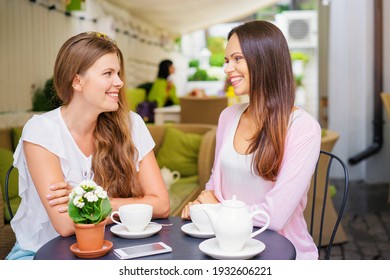 Family Day. Two Adult Sisters Talking While Drinking Tea At Cafe.