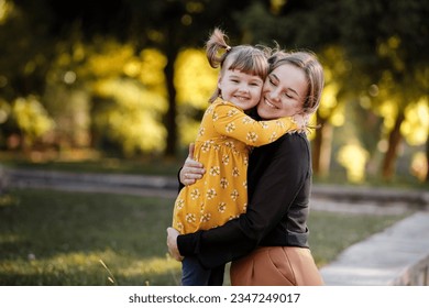 Family day. Young single mother hugging adorable little daughter with love at autumn park. Mom with kid are having fun, spending time together, playing at weekend. Outdoors activity. Children's day. - Powered by Shutterstock