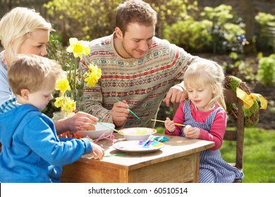 Family Decorating Easter Eggs On Table Outdoors