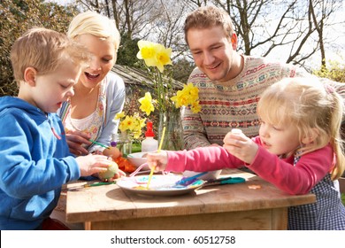 Family Decorating Easter Eggs On Table Outdoors