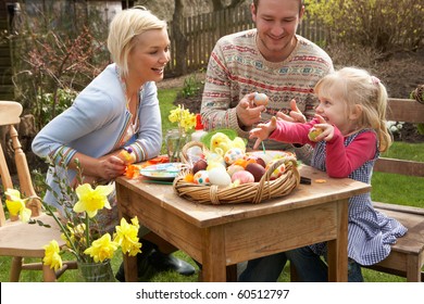 Family Decorating Easter Eggs On Table Outdoors