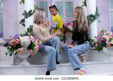 Family From Different Races. Mom Grandmother Fair-skinned And A Little African American Girl Play On The Doorstep Of The House.