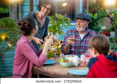 Family Dinner In The Garden In The Evening. Parents And Children Discuss Together