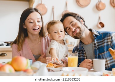 Family Dinner Lunch Breakfast At Home. Caucasian Happy Parents Eating Together, Feeding Small Little Kid Child Toddler New Born Baby Infant At Home Kitchen. Adoption Concept