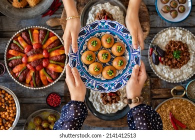 Family dinner with many foods on the table and dessert at the hands of two woman. Dining table with top view.  - Shutterstock ID 2141412513