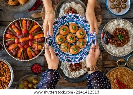 Family dinner with many foods on the table and dessert at the hands of two woman. Dining table with top view. 