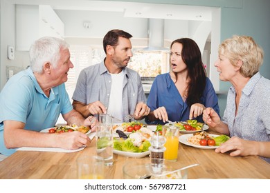 Family Discussing While Sitting At Dining Table In Home