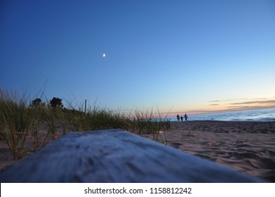 Family In The Distance Walking At Sunset On A Beach 