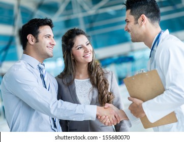 Family doctor handshaking a couple at the hospital 