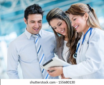 Family Doctor With A Happy Couple At The Hospital 