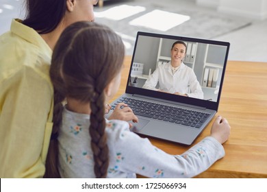 Family Doctor Online. Mother And Girl Kid Talking Consults A Doctor Using A Laptop While Sitting At Home On The Couch.