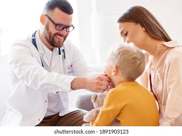 family doctor pediatrician conducts examination of child boy who came with his mother,  looks at his throat 