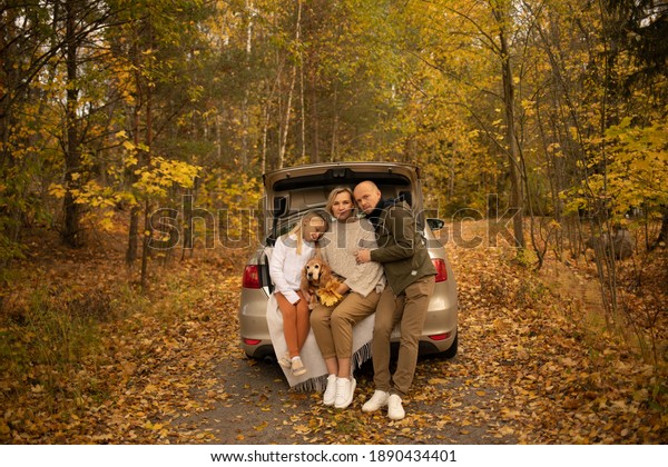 family with a\
dog in a car in autumn in the\
forest