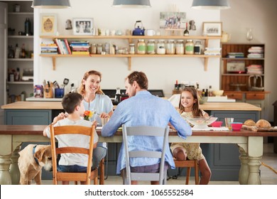 Family With Dog Eating Together At The Table In Kitchen