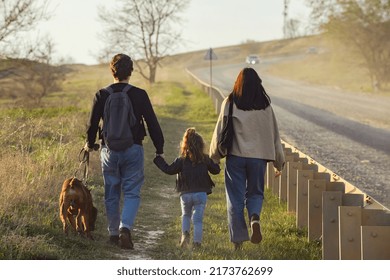 A Family With A Dog Makes A Hiking Trip With A Dog, Travelers With A Child Walk Along A Dusty Road