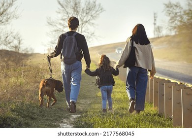 A Family With A Dog Makes A Hiking Trip With A Dog, Travelers With A Child Walk Along A Dusty Road