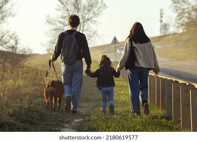 A Family With A Dog Makes A Hiking Trip With A Dog, Travelers With A Child Walk Along A Dusty Road