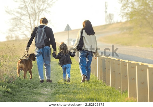 a family with a dog makes a\
hiking trip with a dog, travelers with a child walk along a dusty\
road