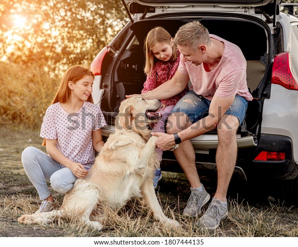 Family with dog next to open\
car