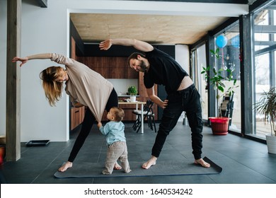 Family doing yoga. Mother and father doing side tilts as a part of their morning exercise, while their child pulling mother's shirt, seeking attention.