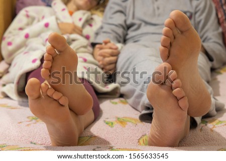 family domestic bed scene of man and woman bare feet foreground and bodies unfocused background 
