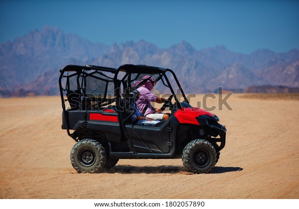 family is driving a buggy car through the\
desert. extreme tourism\
adventures