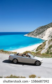 Family Driving Convertible Car Along Winding Coastal Road