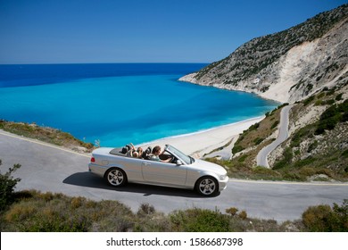 Family Driving Convertible Car Along Winding Coastal Road