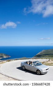 Family Driving Convertible Car Along Winding Coastal Road