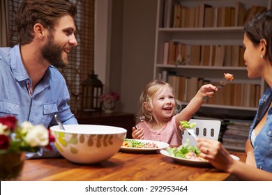 Family Eating An Dinner At A Dining Table