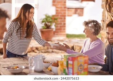 Family, eating and happy in garden for breakfast with serve, hosting and bonding for nutrition or wellness. Senior, women and relax together in backyard or patio in morning with healthy meal or food - Powered by Shutterstock