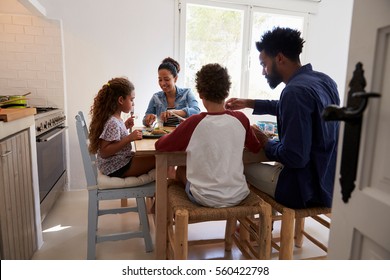 Family eating at kitchen table, back view, seen from doorway