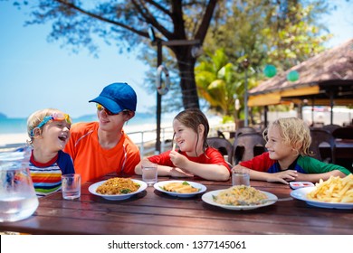 Family Eating Lunch On Tropical Beach. Kids In Outdoor Restaurant Of Exotic Resort In Asia. Asian Food For Children. Young Man, Boy And Girl Eat Dinner At Sea Coast. Holiday With Child.