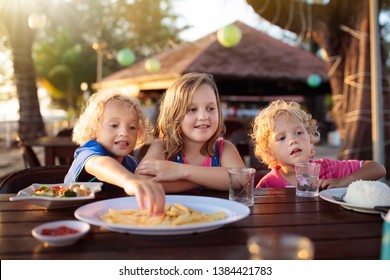 Family Eating Lunch On Tropical Beach. Kids In Outdoor Restaurant Of Exotic Resort In Asia. Asian Food For Children. Little Boy And Girl Eat Dinner At Sea Coast. Holiday With Child.