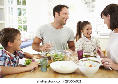 Family Eating Meal Around Kitchen Table Together