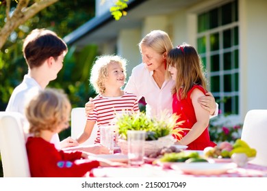 Family Eating Outdoors. Garden Summer Fun. Barbecue In Sunny Backyard. Grandmother And Kids Eat Lunch In Outdoor Deck. Parents And Children Enjoy Bbq. Boy And Girl With Mother.