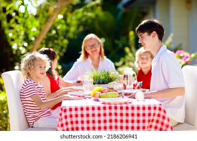 Family Eating Outdoors. Garden Summer Fun. Barbecue In Sunny Backyard. Grandmother And Kids Eat Lunch In Outdoor Deck. Parents And Children Enjoy Bbq. Boy And Girl With Mother.