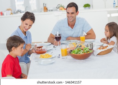 Family Eating Pasta And Salad In The Dining Room