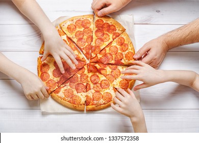 Family Eating Peperoni Pizza. Kids And Fathers Holding A Slice Of Pizza.