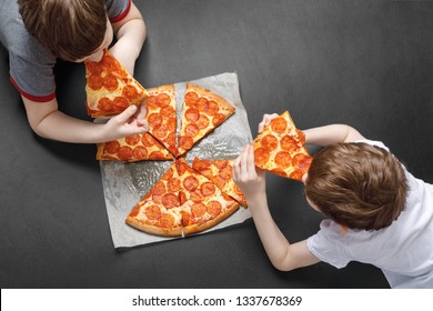 Family eating peperoni pizza. Kids holding a slice of pizza. - Powered by Shutterstock