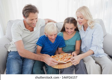 Family Eating Pizza Together Sitting On A Couch