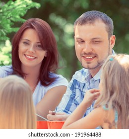 Family Eating Together Outdoors At Park On Backyard. Vintage Style Photo