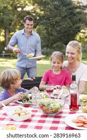 Family Enjoying Barbeque In Garden Together