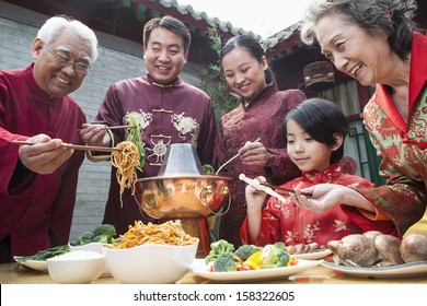 Family Enjoying Chinese Meal In Traditional Chinese Clothing